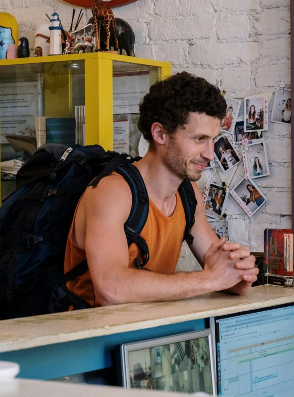 A backpacker checking into a cozy hostel with vibrant decor and friendly atmosphere.